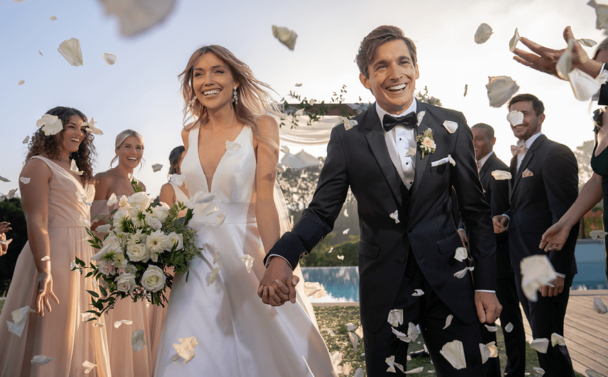 A newly married couple walking through the confetti.