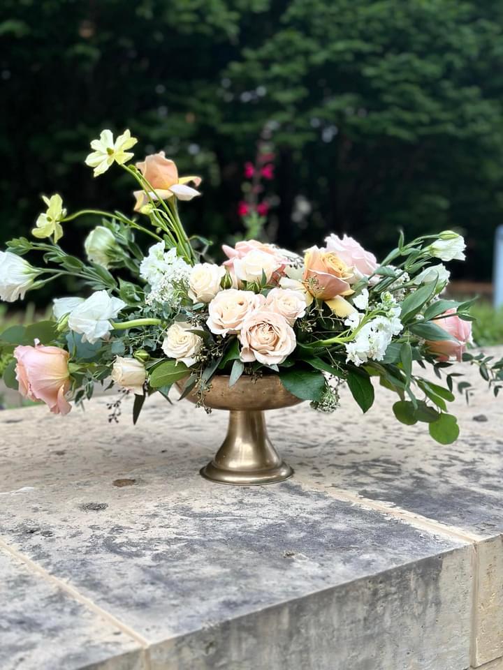 A gold vase filled with flowers on top of a stone surface.