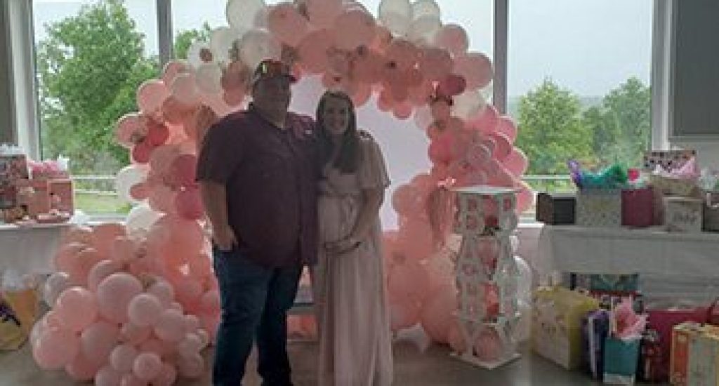 A man and woman standing in front of balloons.